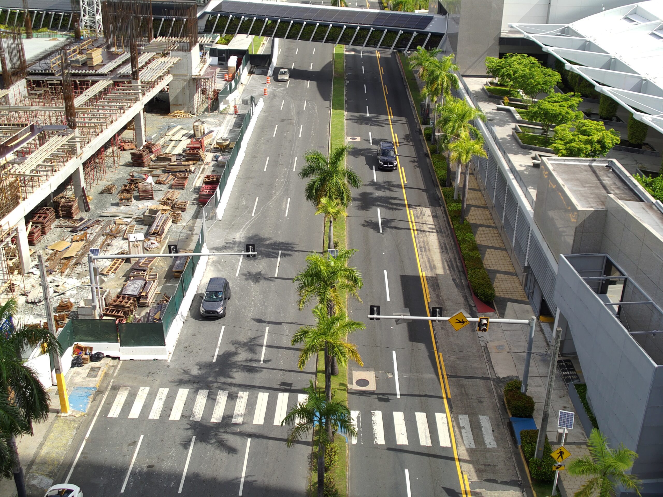 S1016638 A front view from building roof showing road with 3 cars and a under construction building on left side of the road